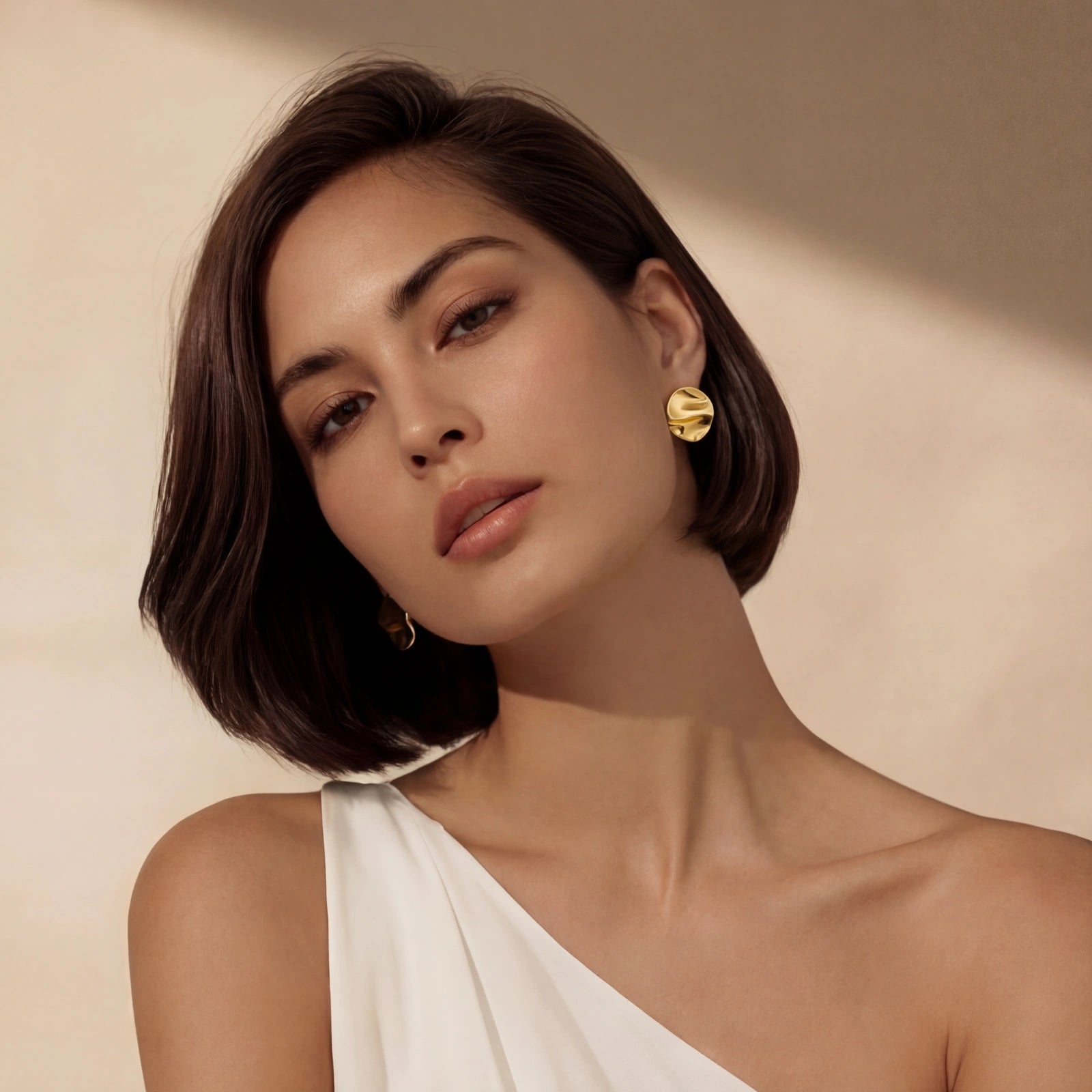 Woman wearing flow statement stud earrings — bold sculptural gold jewelry