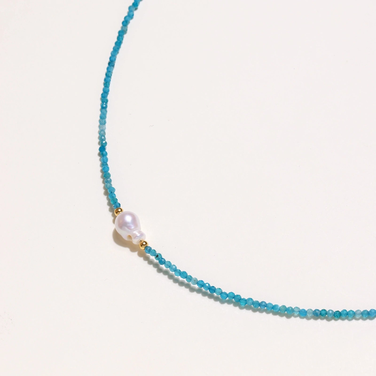 Close-up of baroque freshwater pearl with 18K gold vermeil accents on apatite beaded necklace