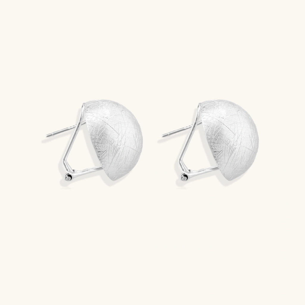 Angled view of brushed silver dome earrings showing matte texture and omega clip closure by VAHN Jewels