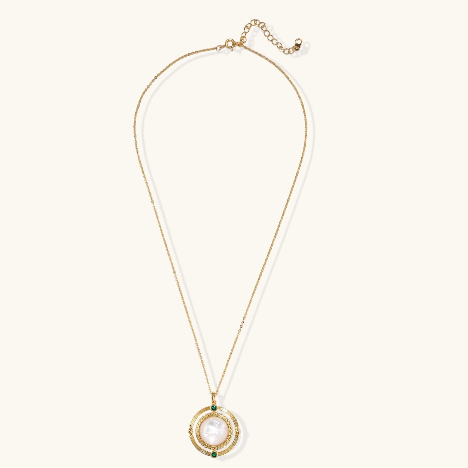 Close-up of hand-etched orbital pendant with mother of pearl disc and emerald zirconia accents