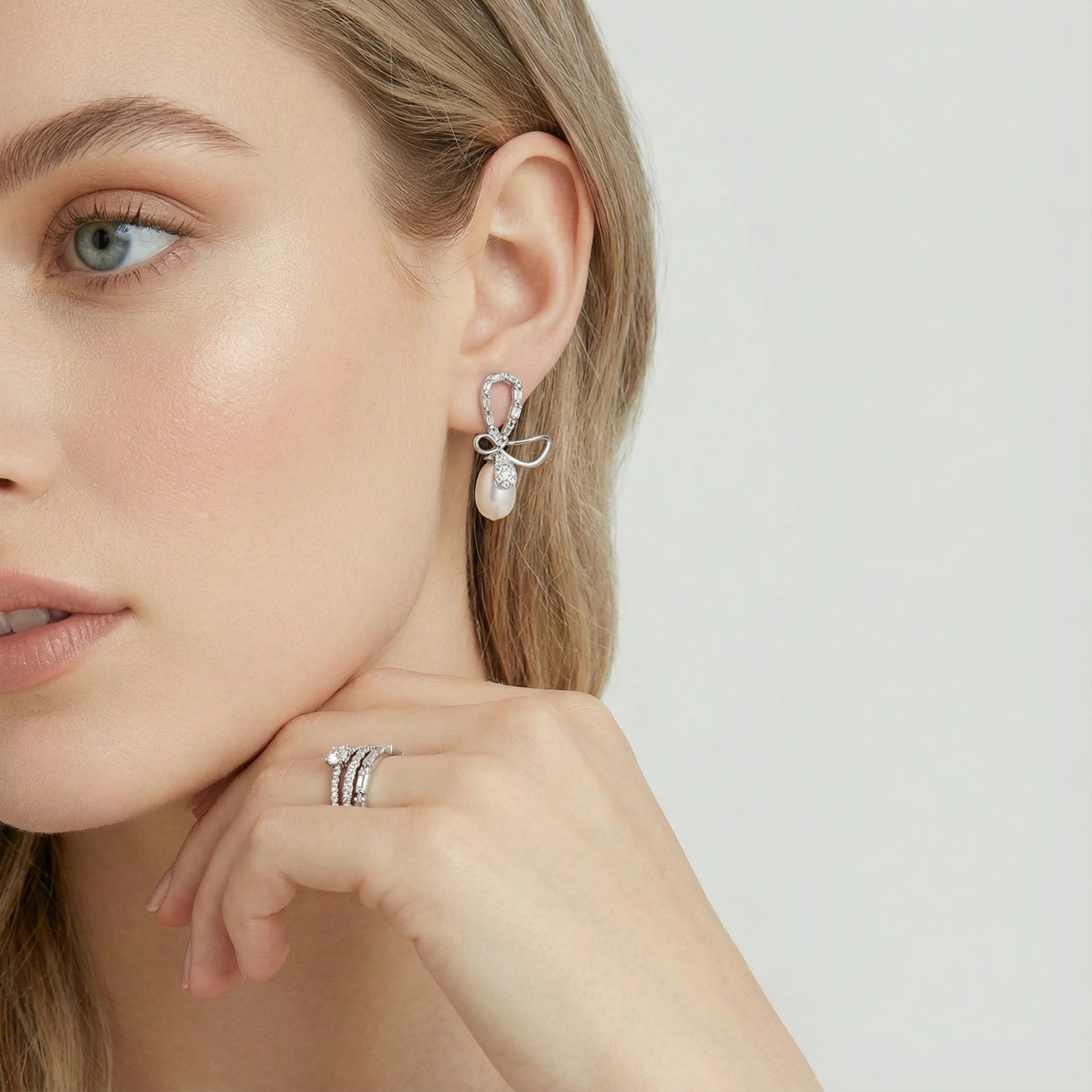 Woman wearing crystal bow pearl drop earrings in silver | VAHN Jewels