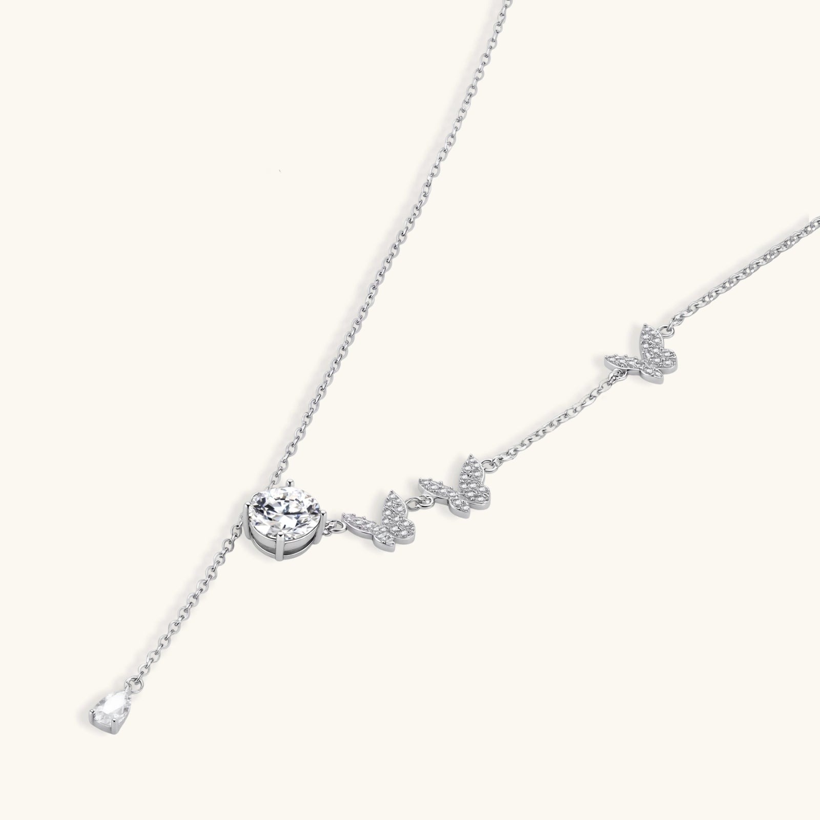 Close-up of pave butterfly charms and 1ct VVS1 moissanite drop on Flutter Dreams 925 sterling silver lariat necklace by VAHN Jewels