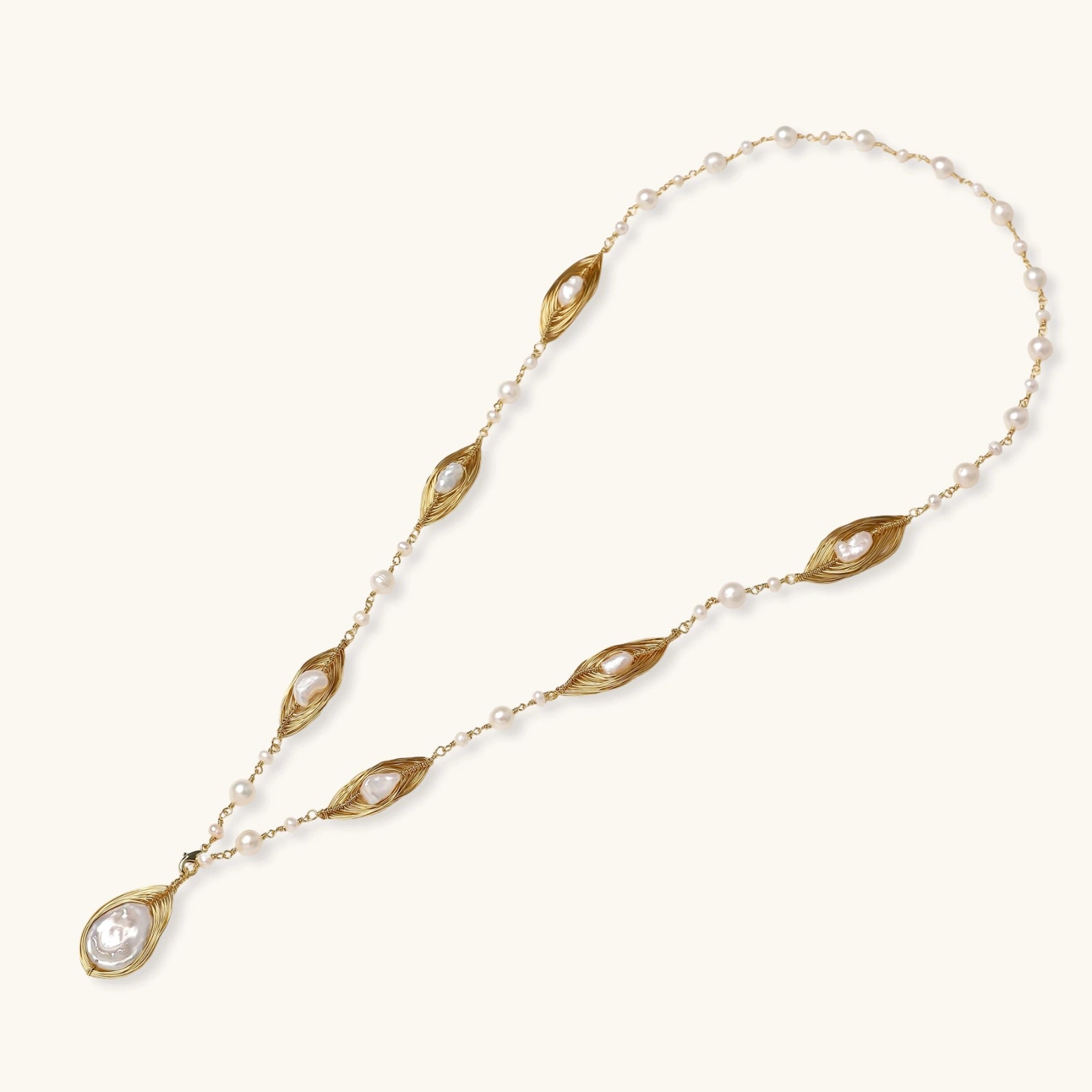 Flat lay of golden cage baroque pearl sautoir in 14K gold plated eco-brass with freshwater pearl chain