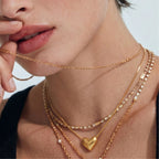 Woman wearing golden heart pendant necklace layered on neckline in 18K gold 925 silver by VAHN Jewels
