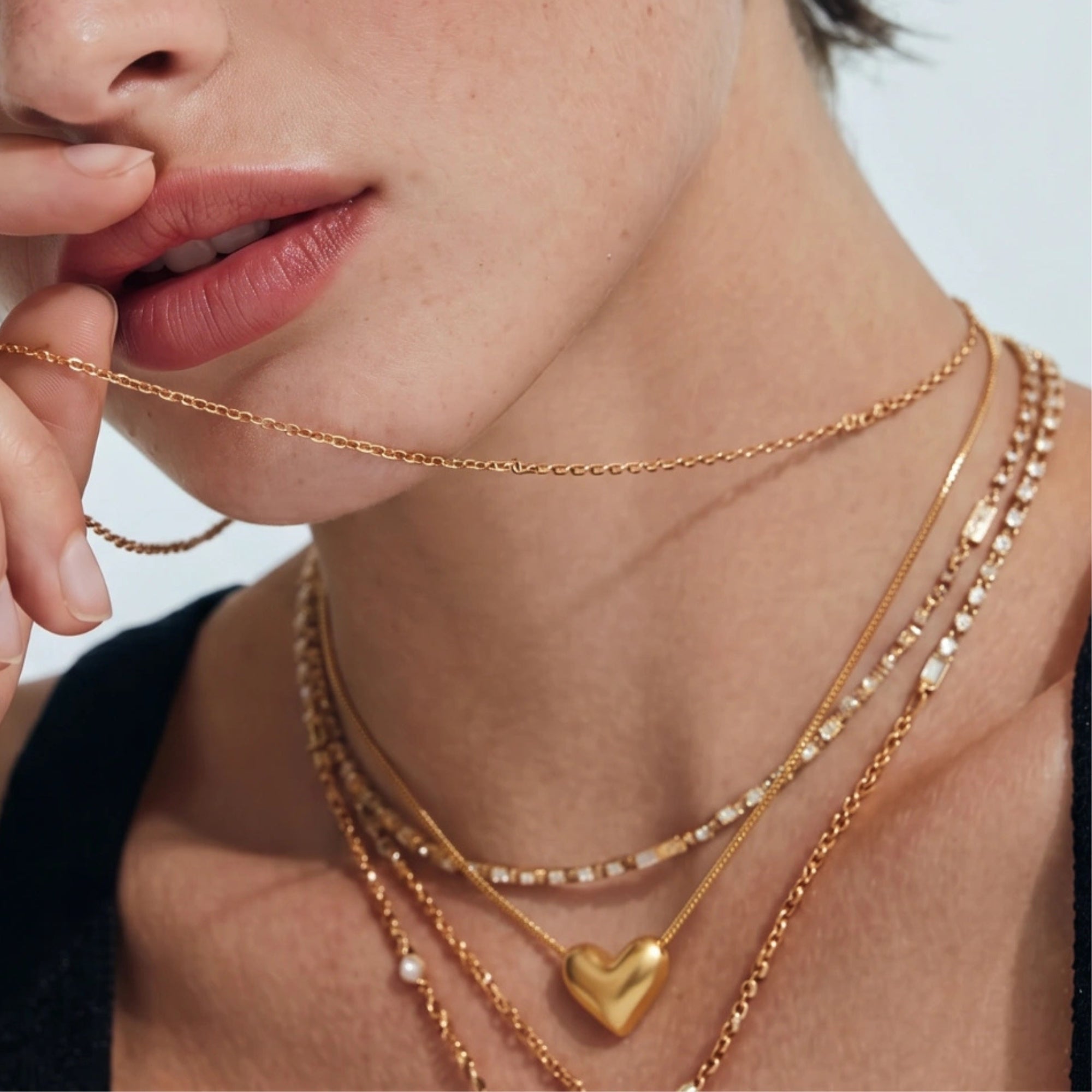 Woman wearing golden heart pendant necklace layered on neckline in 18K gold 925 silver by VAHN Jewels
