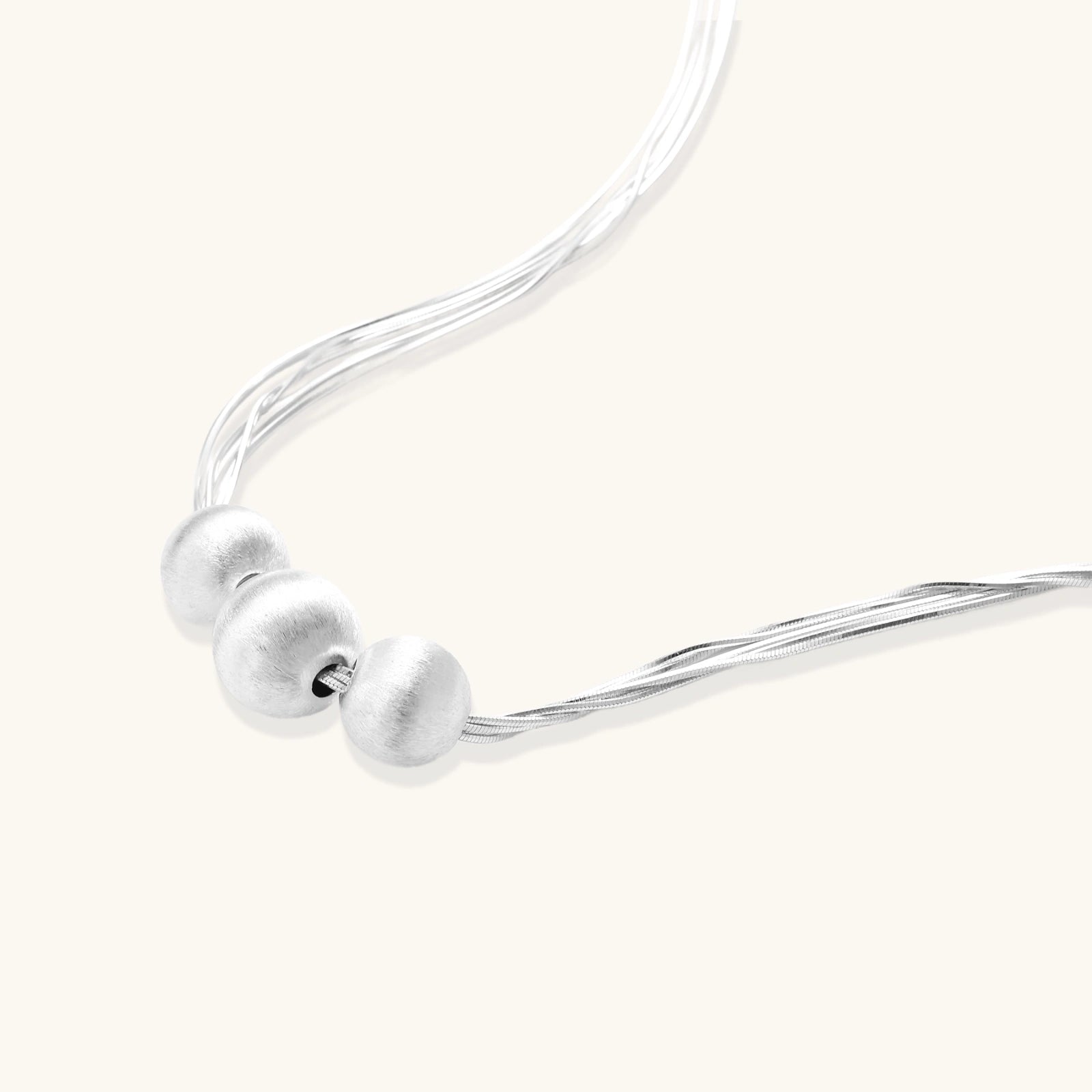 Detail of three brushed silver beads on multi-strand sterling silver chain