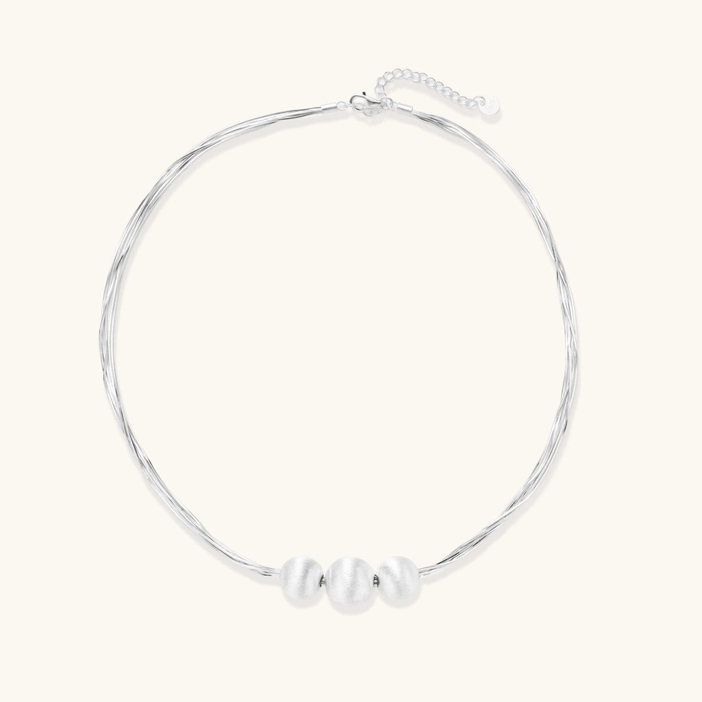 Flat lay of brushed silver multi-strand necklace with three silver beads in sterling silver 925
