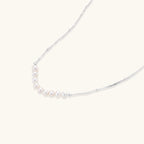 Close-up of nine freshwater pearls aligned in a dainty crescent on rhodium-plated 925 silver chain by VAHN Jewels