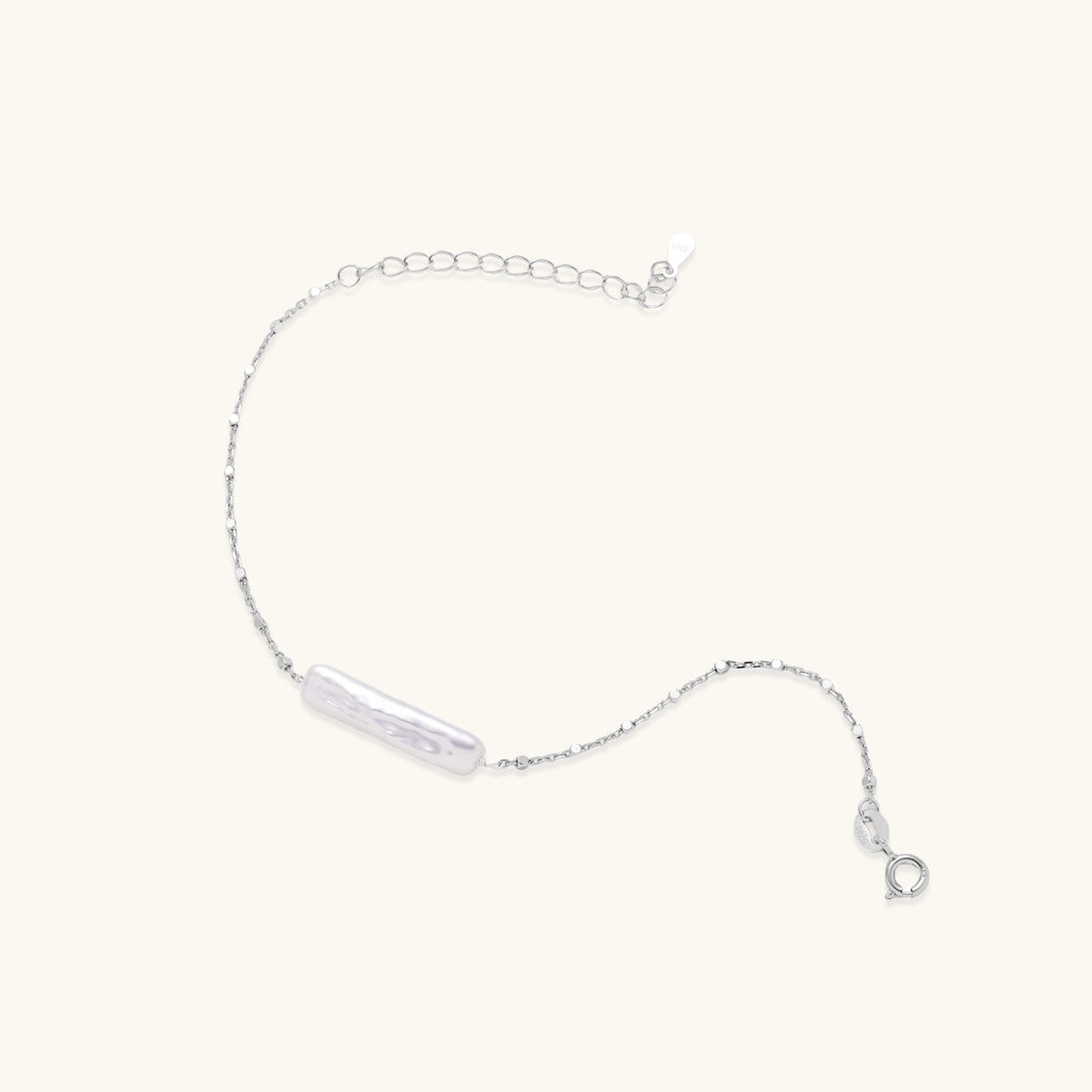 Close-up of single baroque pearl suspended on fine rhodium-plated silver chain