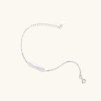 Close-up of single baroque pearl suspended on fine rhodium-plated silver chain