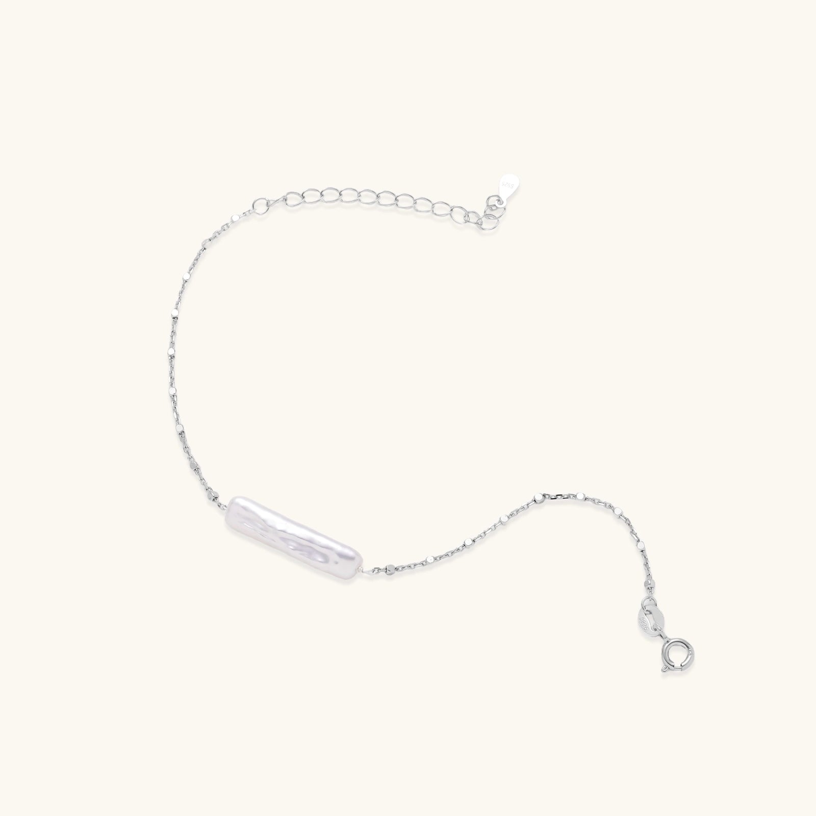 Close-up of single baroque pearl suspended on fine rhodium-plated silver chain