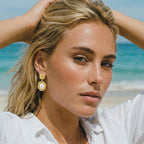 Woman wearing golden bloom pearl drop earrings in 18K gold-plated 925 sterling silver by VAHN Jewels