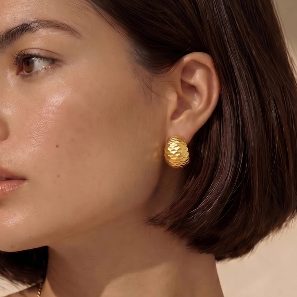 Woman wearing hammered gold huggie earrings in 18K gold-plated 925 sterling silver by VAHN Jewels