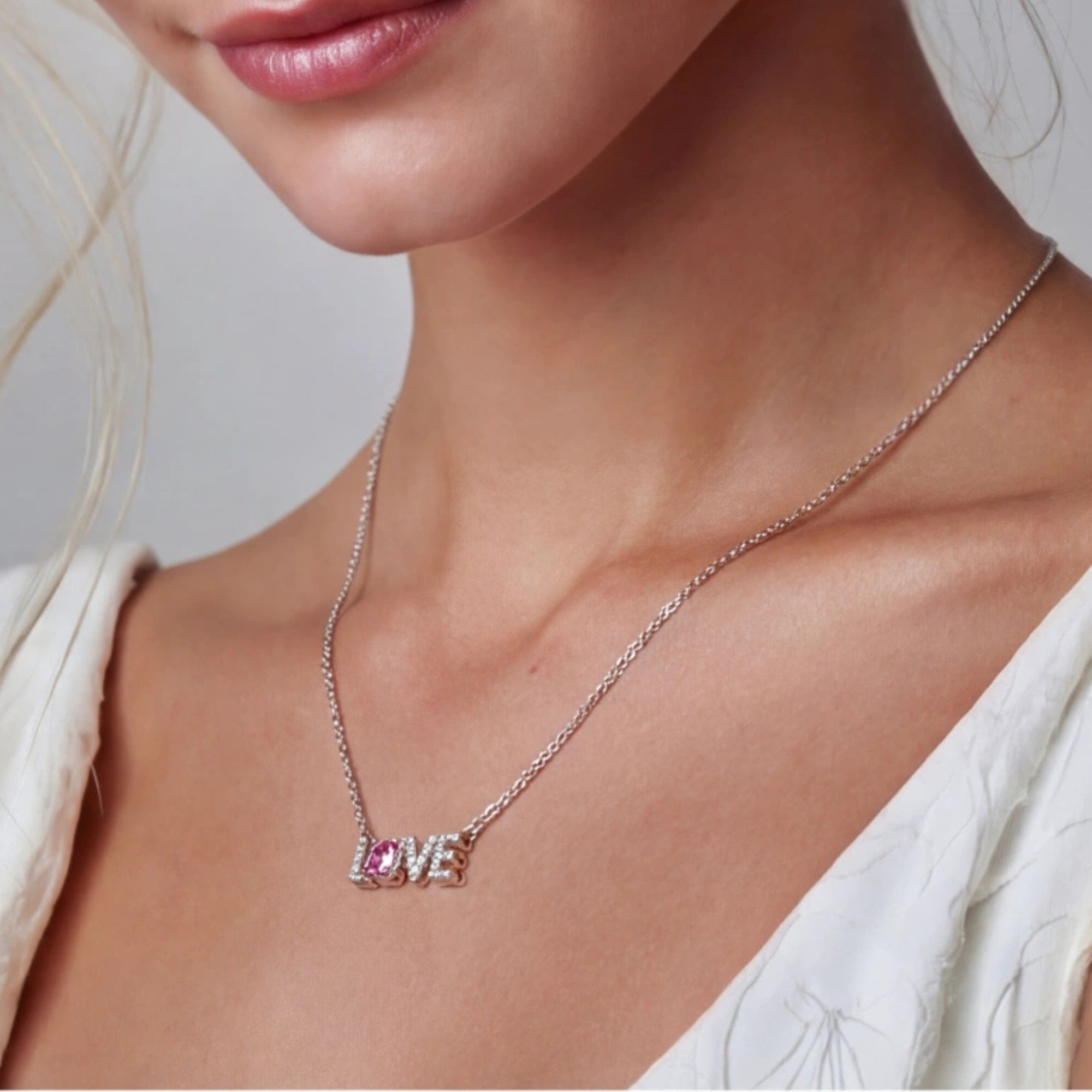 Woman wearing LOVE moissanite pendant necklace in 925 sterling silver with pink moissanite by VAHN Jewels
