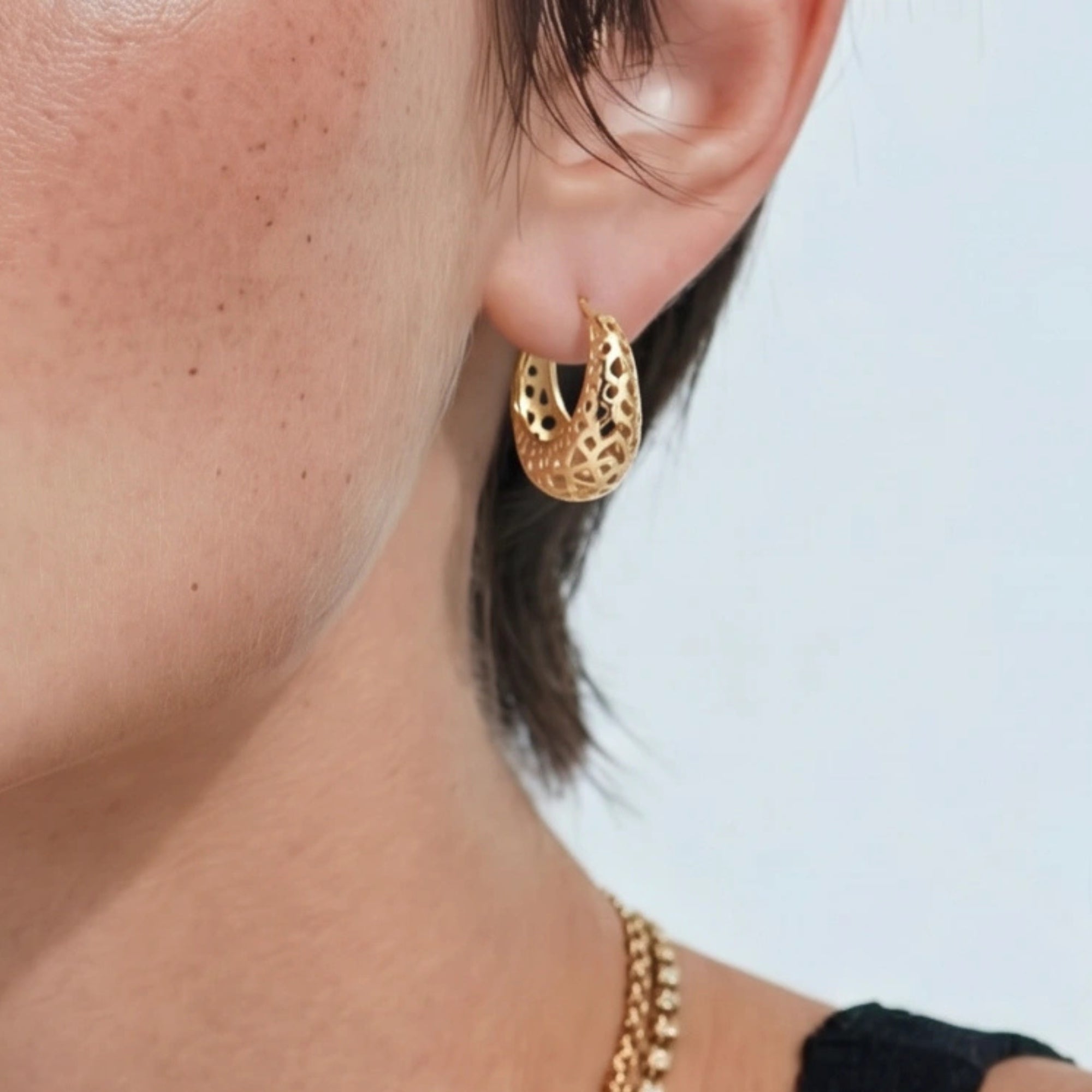 Woman wearing openwork gold dome hoop earrings in 14K gold-plated 925 sterling silver by VAHN Jewels