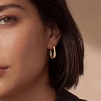 Woman wearing pave gold huggie hoop earrings in 14K gold-plated 925 sterling silver by VAHN Jewels