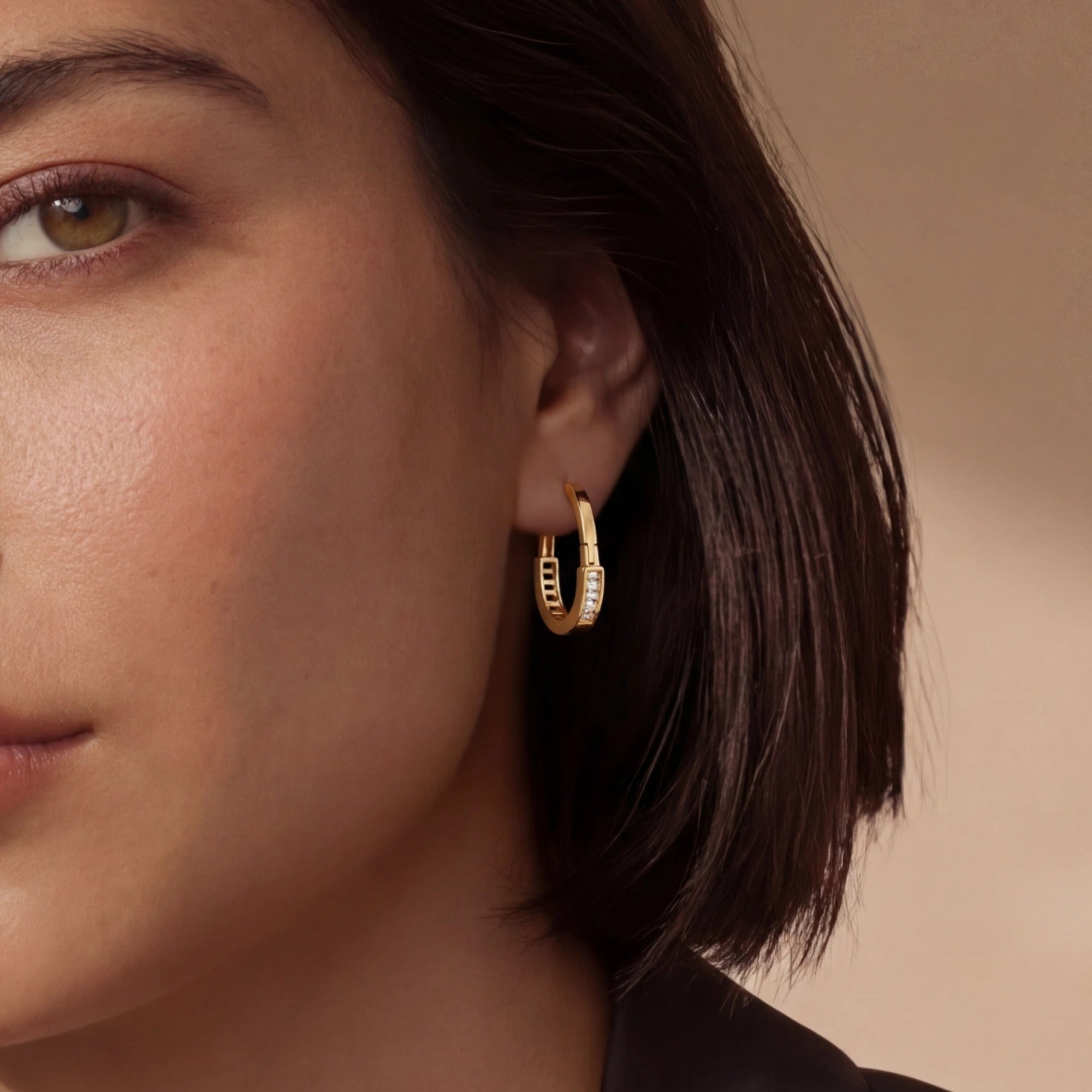 Woman wearing pave gold huggie hoop earrings in 14K gold-plated 925 sterling silver by VAHN Jewels