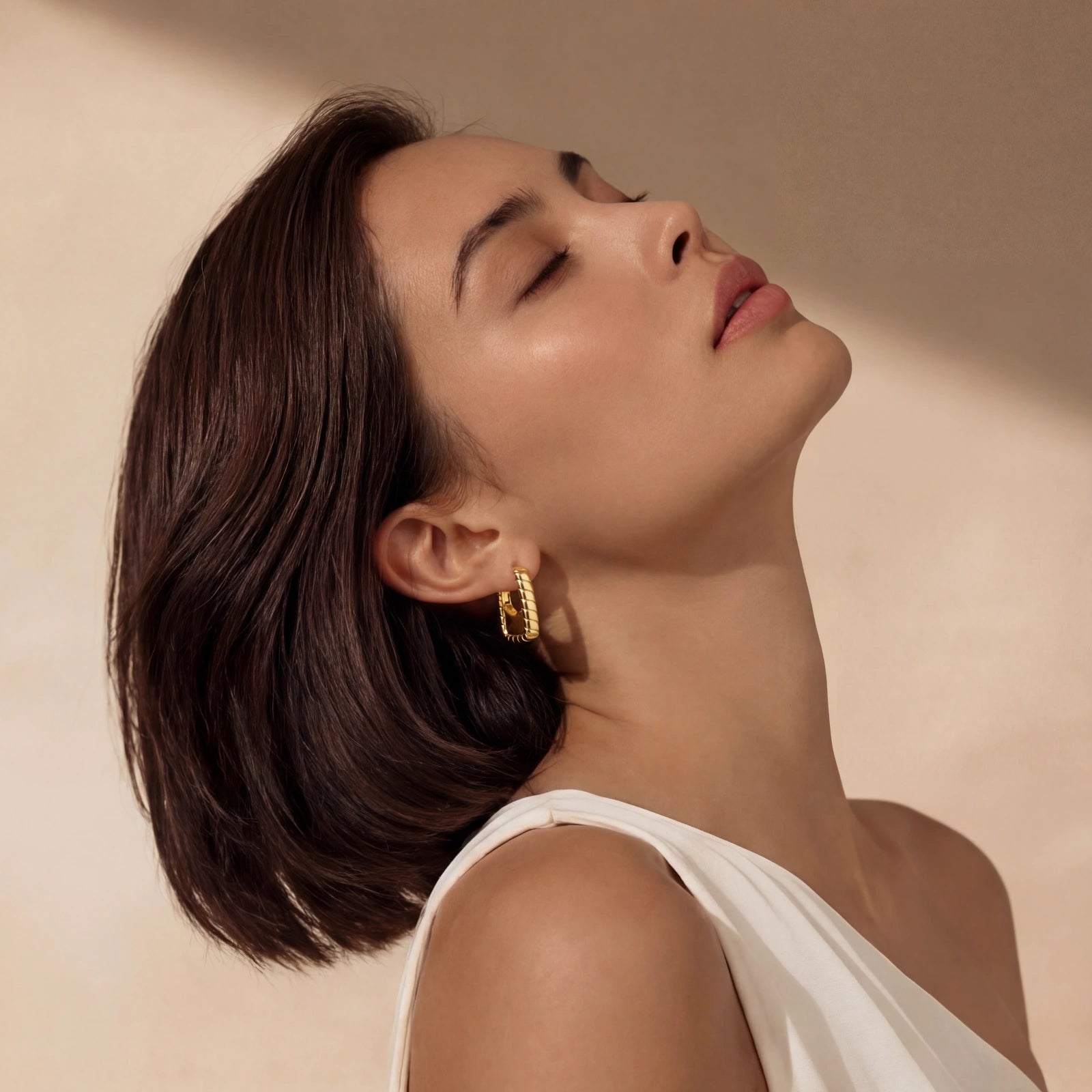 Woman wearing bamboo huggie hoop earrings — bold gold statement jewelry