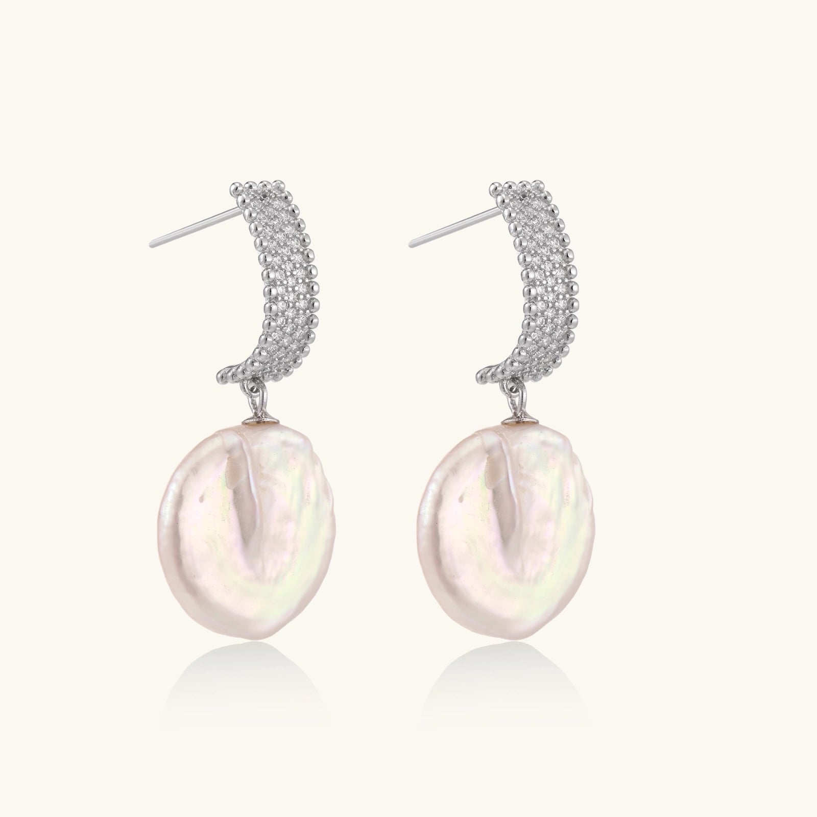 Close-up of geometric silver bead stud with baroque pearl drop earrings