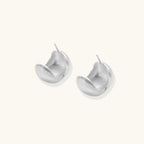 Close-up of brushed satin finish on sterling silver sculptural stud earrings