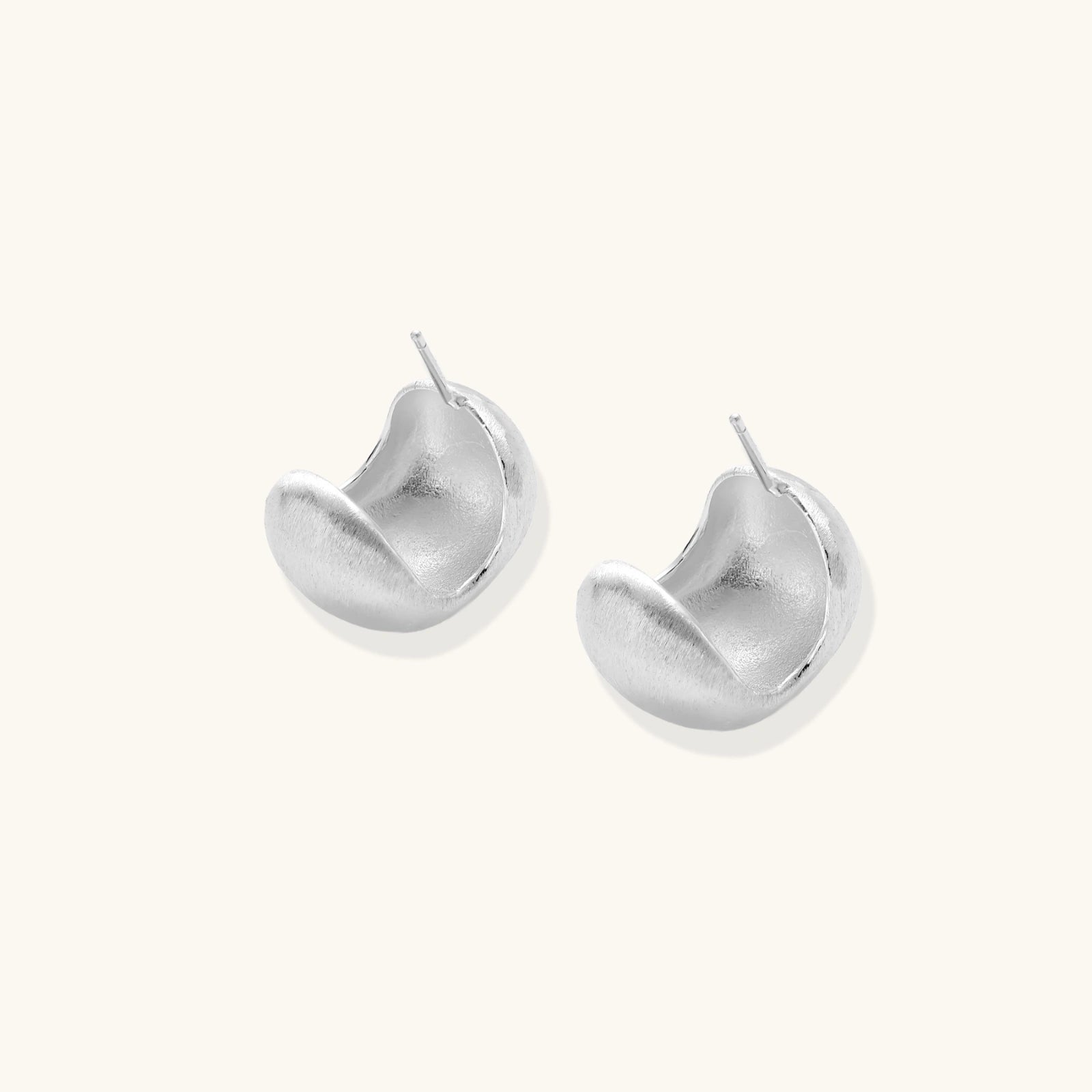 Close-up of brushed satin finish on sterling silver sculptural stud earrings