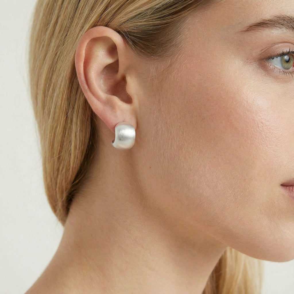  Woman wearing brushed silver stud earrings — minimalist luxury jewelry