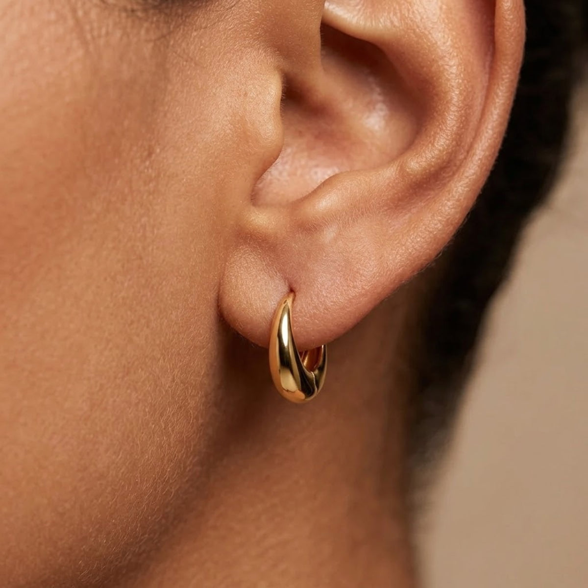 Small gold teardrop huggie earring worn on the ear | VAHN Jewels