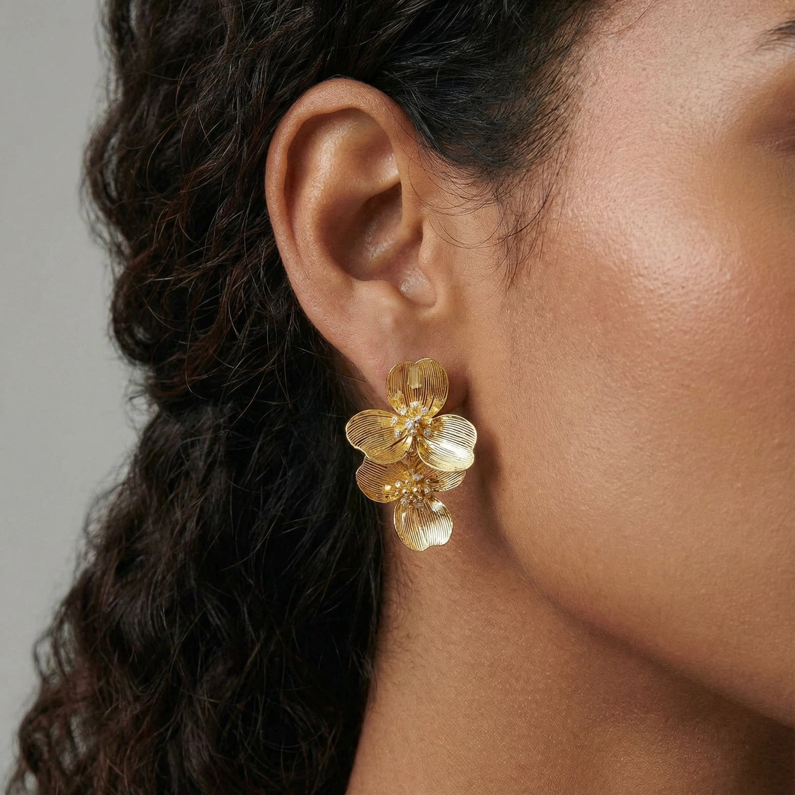 Woman wearing golden bloom double earrings — bold floral statement jewelry
