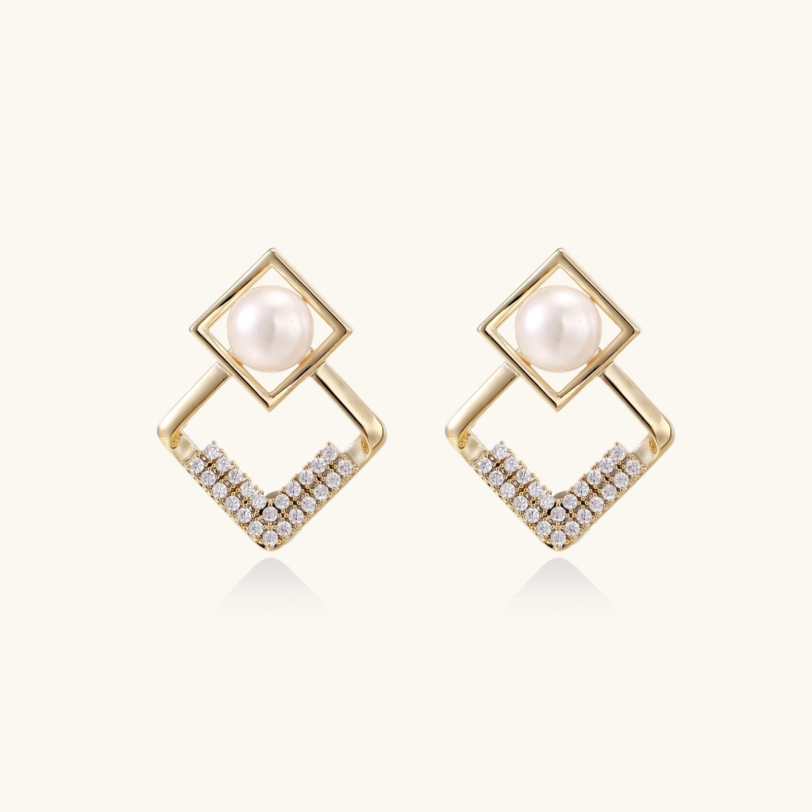 Pearl geometry earrings with double gold frame and pavé crystals on white background