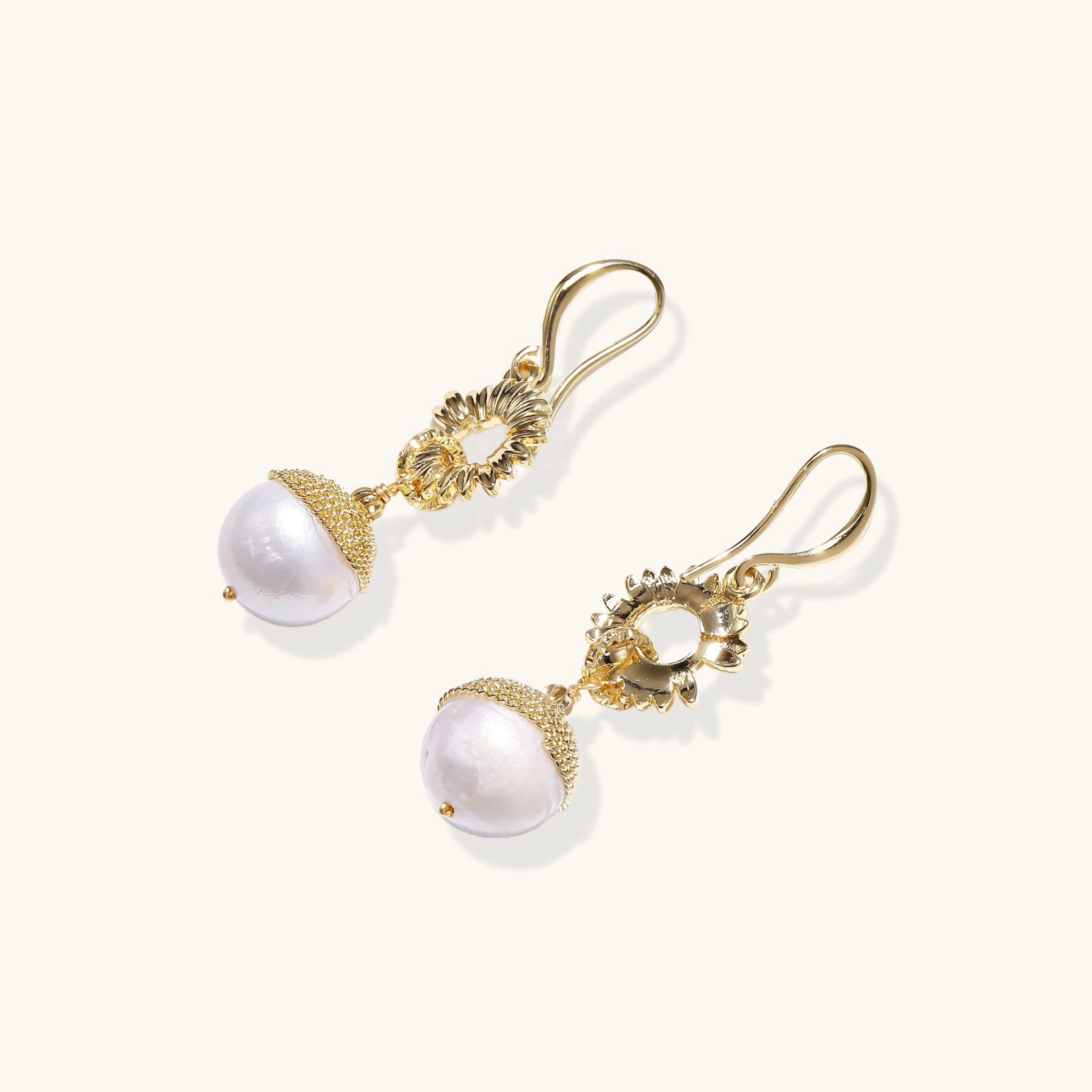Detail shot of baroque pearl drop beneath gold sunburst earring charm